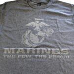 a charcoal gray USMC t-shirt with a large Eagle, Globe, & Anchor, plus the text "MARINES" "THE FEW THE PROUD." The print is light gray and reflective.